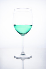 Green cocktail in a glass on a white background with reflection