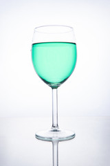 Green cocktail in a glass on a white background with reflection