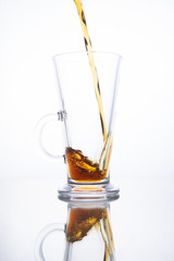 Dark beer is poured into an empty mug on a white background.  Splash fluid