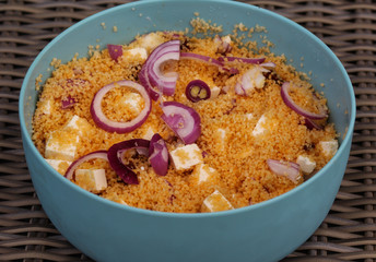 Bowl with couscous salad served with red onion, feta cheese and sun dried tomato