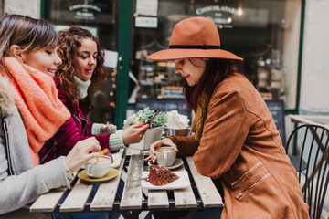 Three women friends having coffee in a terrace in Oporto, Portugal. Having a fun conversation. Lifestyle, tourism and holidays