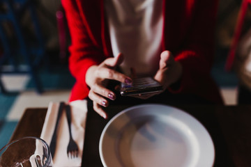 young unrecognizable caucasian woman using mobile phone in a restaurant. Technology and lifestyle