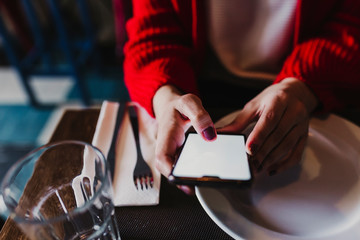 young unrecognizable caucasian woman using mobile phone in a restaurant. Technology and lifestyle