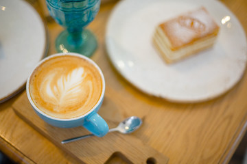 Slice of sweet tasty Honey Cake Medovik and blue cup of cappuccino on the wooden table