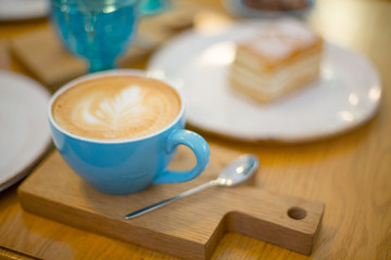 Slice of sweet tasty Honey Cake Medovik and blue cup of cappuccino on the wooden table