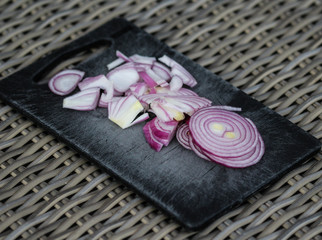 fresh healthy chopped red onion on white cutting board on wooden background