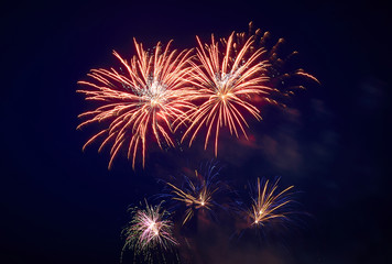 Fototapeta premium A few volleys of festive fireworks in the night sky, red-yellow