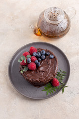 Chocolate cake with raspberry on gray plate on bright background