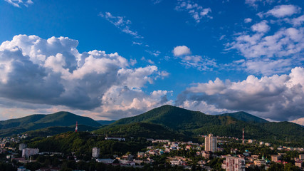 Fototapeta na wymiar City against the backdrop of mountains and blue sky.