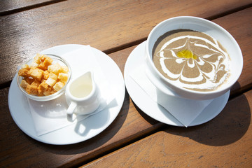 Delicious mushroom cream soup with croutons on a wooden table