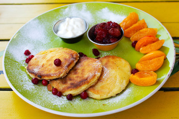 Cottage cheese pancakes with dried fruit and sour cream. Traditional Breakfast in the morning.