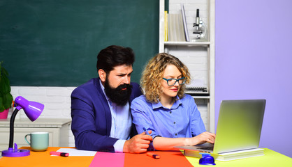 School students. Two creative happy smiling students in auditorium. Happy casual girl student with bearded hipster teacher. University students at college. Students couple preparing for test or exam.