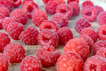 Fresh organic raspberries background closeup. Fresh raspberries on wooden background; berries are lit with the daylight