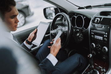 Young handsome man in his car using gadgets