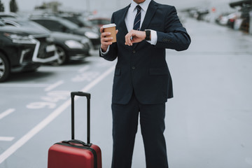 Young guy in suit staying on the parking lot outdoors
