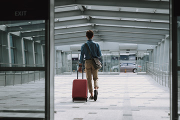 Young man in casual wear walking along corridor in airport