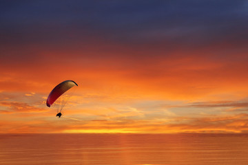 colored parachute flies in the sky against the backdrop of the sea at sunset, Zen, harmony, balance. ocean at sunset in the background travel, flight, vacation Concept