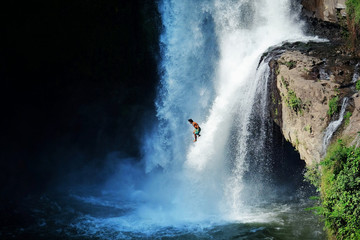 Jumping into the water. Man having fun at waterfalls in the nature. Bali, Indonesia - obrazy, fototapety, plakaty