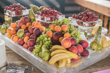 Buffet line assorted Fruit platter of strawberries Grapes Blueberries Peaches Apricot Banana Cherry Pears on ice. View from side.