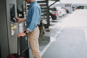 Young guy making payment with mobile phone in the parking