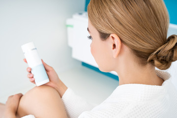 Close up of the woman looking at the label on her cream bottle