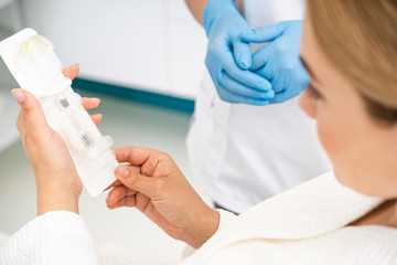 Female patient holding injection set in the medical office