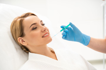 Beauty injection into the chin of smiling female patient