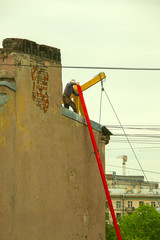 the man raises the board on the winch to the roof for repair