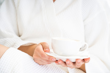 Cropped photo of Caucasian woman holding cup of tea in arms