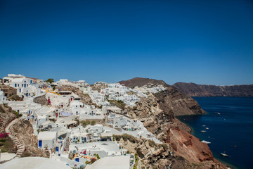 Fototapeta na wymiar Oia town on Santorini island, Greece. View of traditional white houses and churches with blue domes over the Caldera