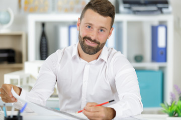 male architect with pencil studying plans in loft office