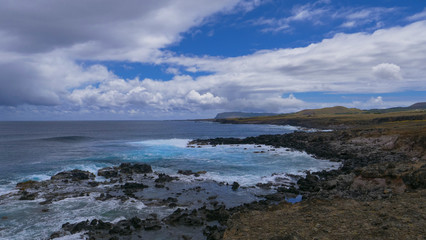 Fototapeta na wymiar AERIAL: Picturesque view of the blue sky above the coastline of volcanic island.