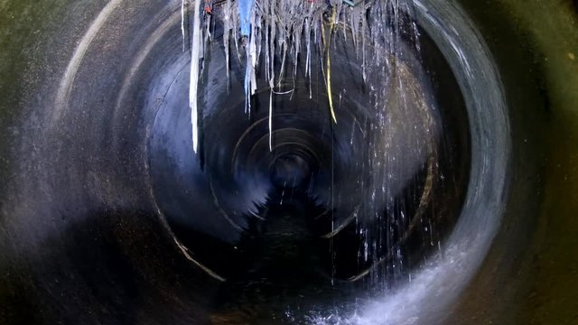 Dark underground sewer round concrete tunnel. Industrial wastewater and urban sewage flowing throw sewer pipe