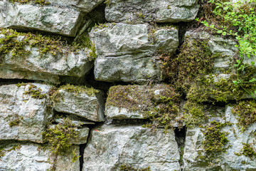 Ancient stone wall overgrown with grass and moss.