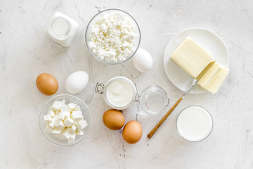 Fresh dairy products for breakfast with milk, cottage, eggs, butter, yougurt on white marble background top view mock up