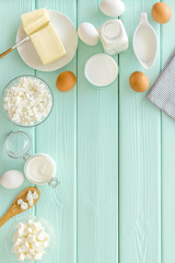 Fresh dairy products with milk, cottage, eggs, butter, yougurt on mint green wooden background top view mock up