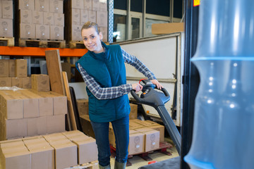 female worker pushing trolley with boxes in warehouse