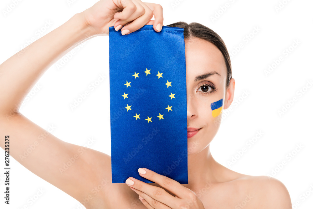 Wall mural naked young woman with painted Ukrainian flag on face holding flag of Europe isolated on white