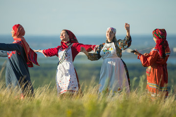 Young women in traditional russian clothes dancing on the field