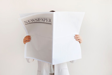 Woman reading newspaper on white background