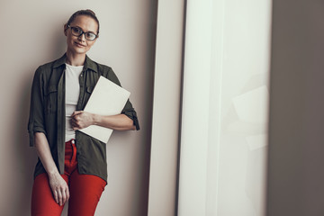 Happy young lady in glasses is holding laptop
