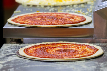 Cook in the kitchen putting the ingredients on the pizza. Production and delivery of food.