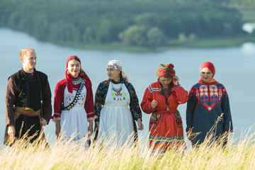 People in traditional russian clothes standing on the field - a man holding a balalaika