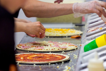 Cook in the kitchen putting the ingredients on the pizza. Production and delivery of food.