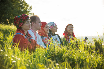 People in traditional russian clothes standing on the field in high grass - obrazy, fototapety, plakaty