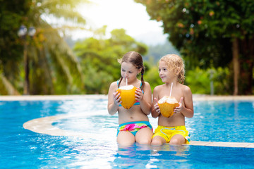Child with coconut drink. Kids in swimming pool.