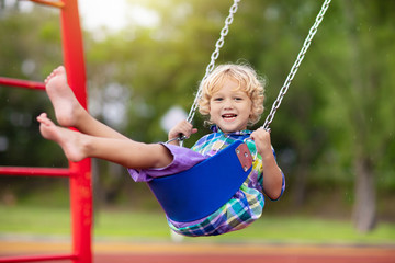 Child on playground. swing Kids play outdoor.