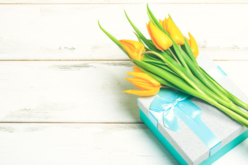 greeting card yellow tulips on turquoise gift box on a white wooden background. Scandinavian style, place for text.