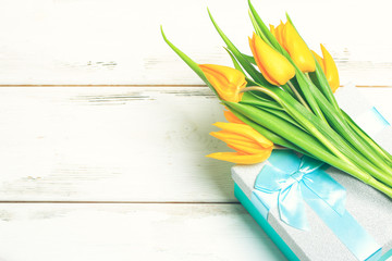 greeting card yellow tulips on turquoise gift box on a white wooden background. Scandinavian style, place for text.