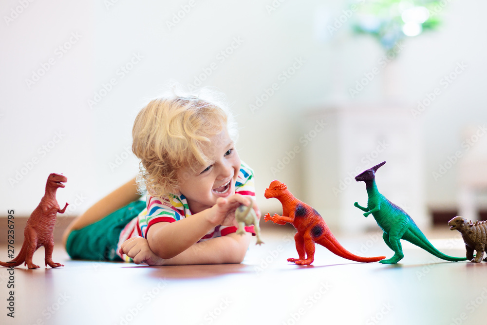 Wall mural child playing with toy dinosaurs. kids toys.